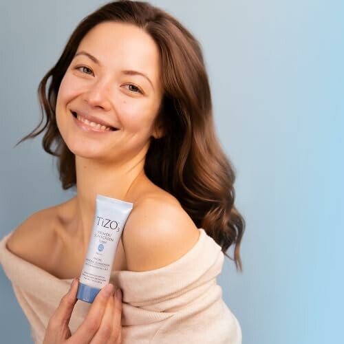 Smiling woman holding a Tizo skincare product